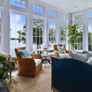 A bright sunroom with a large MI window framing a clear view of a lush green garden.