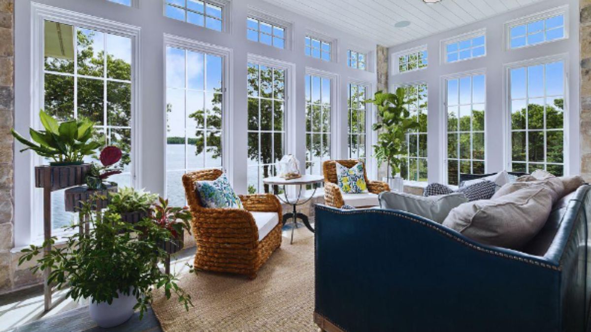 A bright sunroom with a large MI window framing a clear view of a lush green garden.