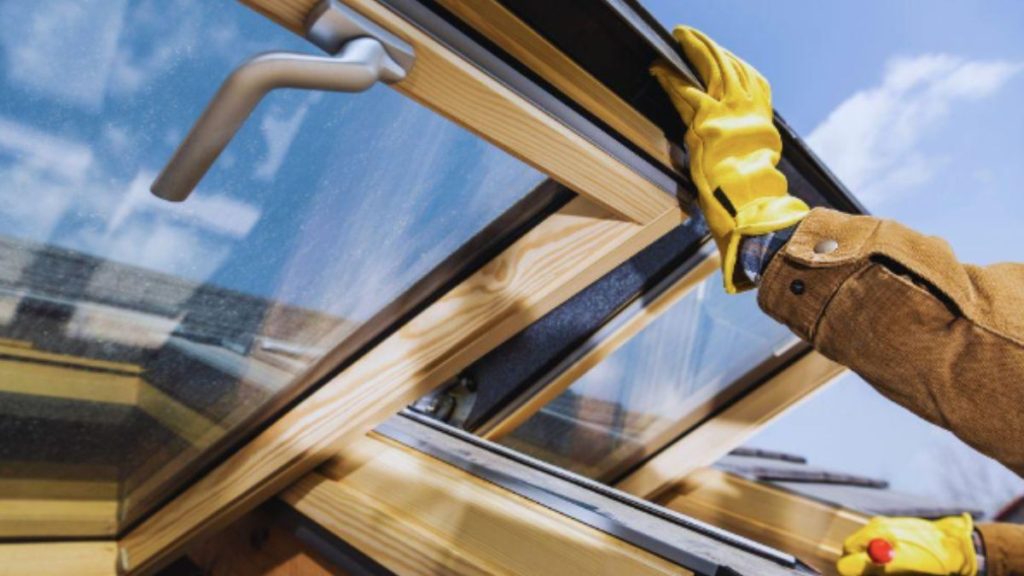 A professional installer, clad in yellow gloves, carefully fits a skylight, demonstrating the precision of MI window installations.