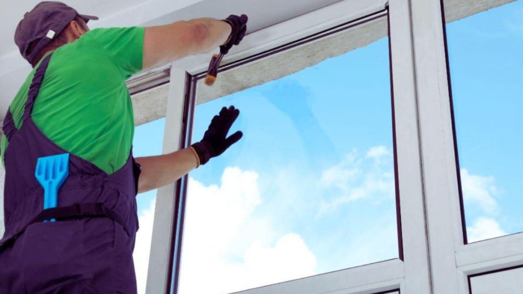 A man in overalls diligently cleans windows, showcasing his commitment to maintaining a clear view.