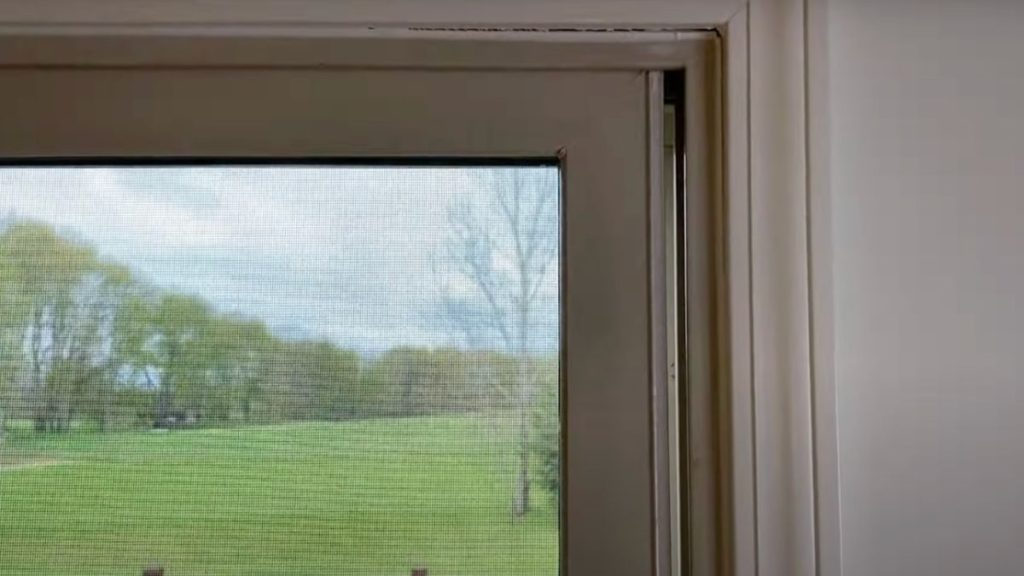 A scenic view of a lush golf course visible through a large window, showcasing green fairways and distant trees.