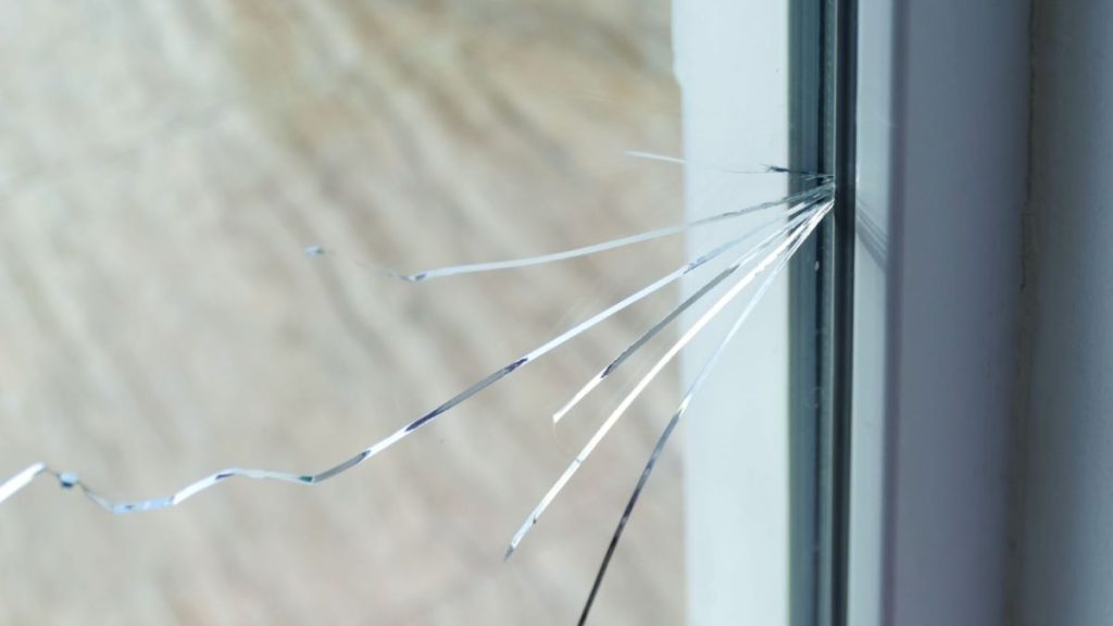 A broken window featuring shattered glass and a damaged window frame, illustrating neglect and disrepair.