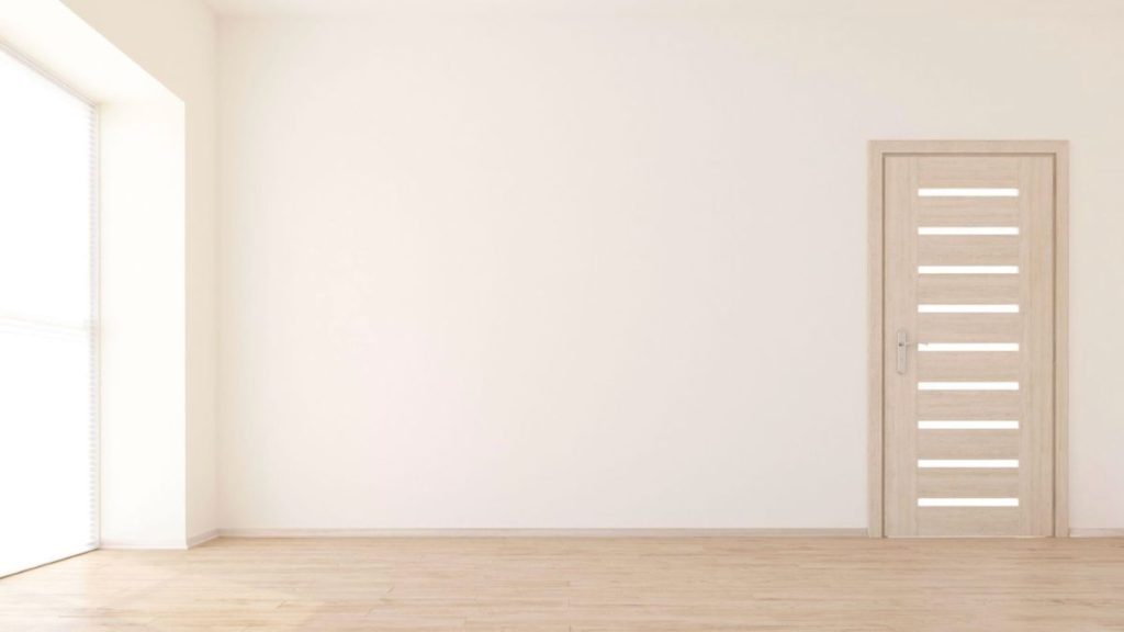 A vacant room featuring white walls and a polished wooden floor, creating a bright and airy atmosphere.