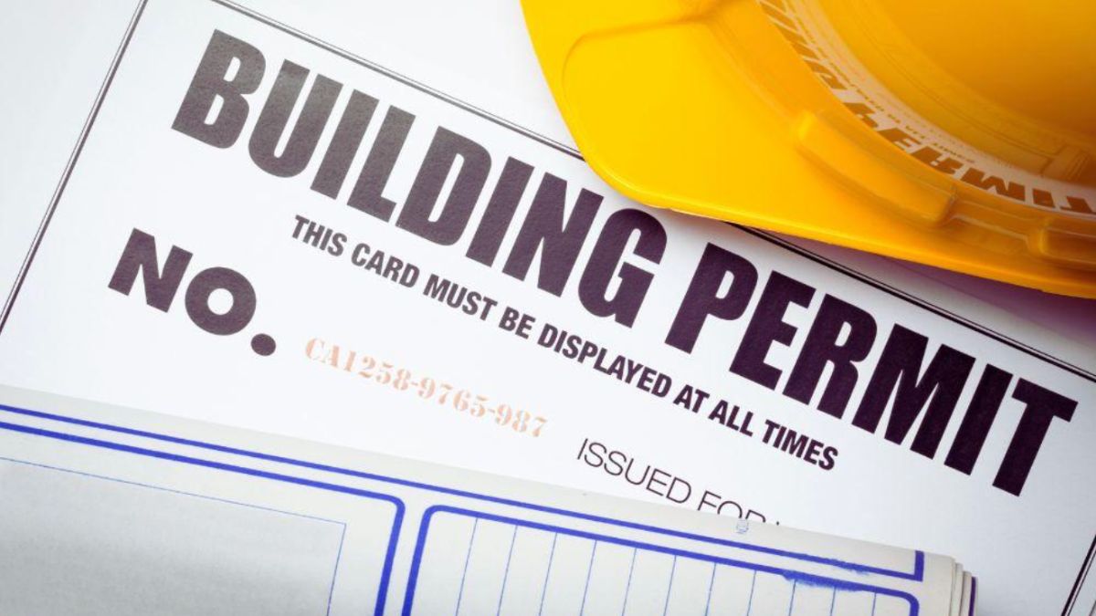 A building permit document displayed on a desk in an office setting, indicating approval for construction.