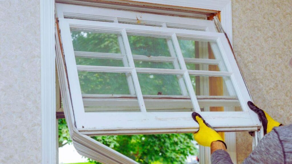 A person installing a window in a house, demonstrating home improvement and construction skills.