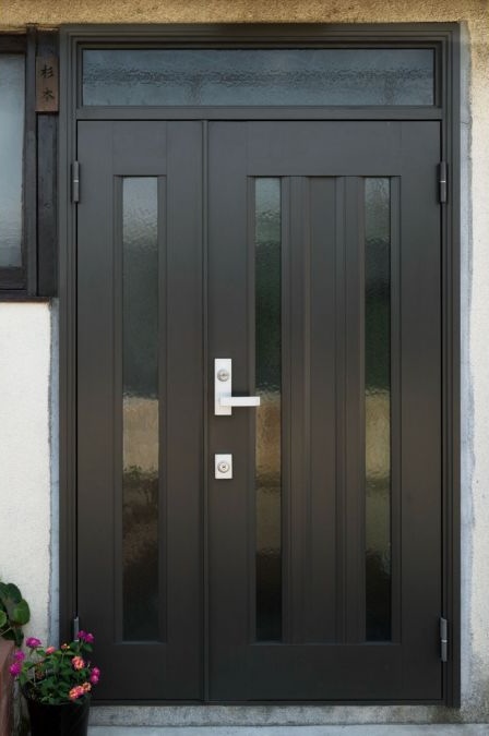 A sleek black fiberglass entry door with a flower pot beside it showcasing a welcoming entryway.