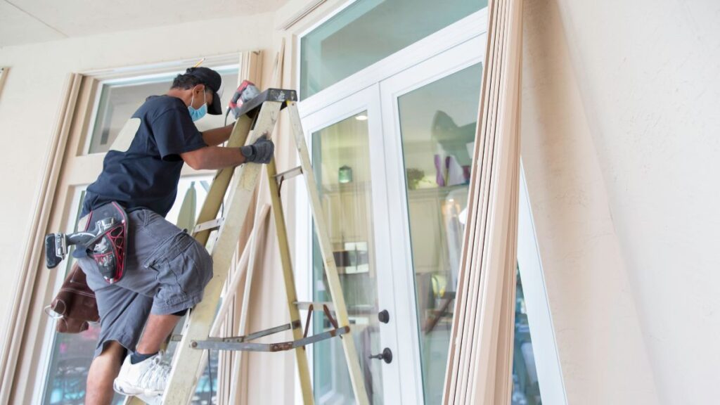 A man in overalls works on a window, demonstrating the quality of professional window installation services.