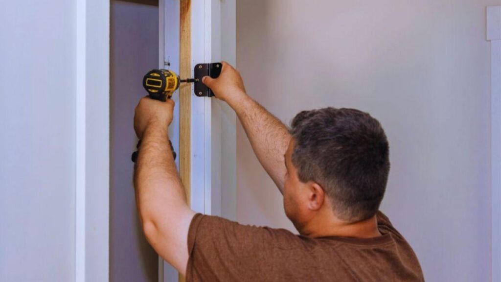 A person using a power drill to install hardware for a pocket door or a sliding door that tucks into the wall.