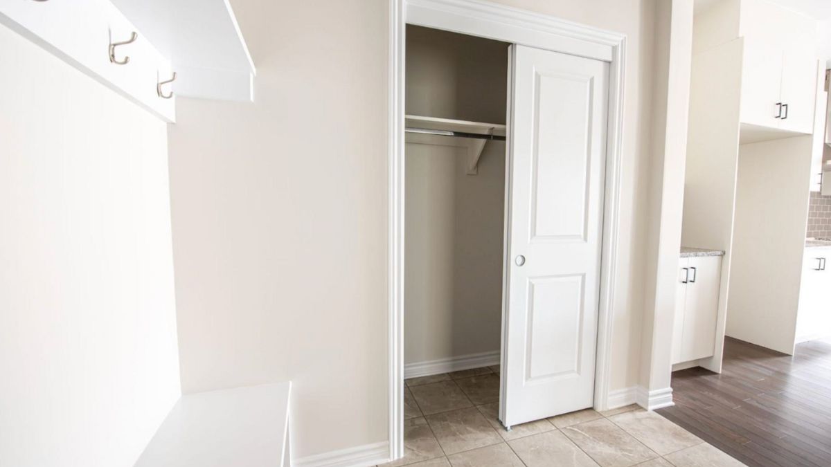 Image of an interior with a pocket door leading to a closet, tiled flooring, white trim, and neutral tones.