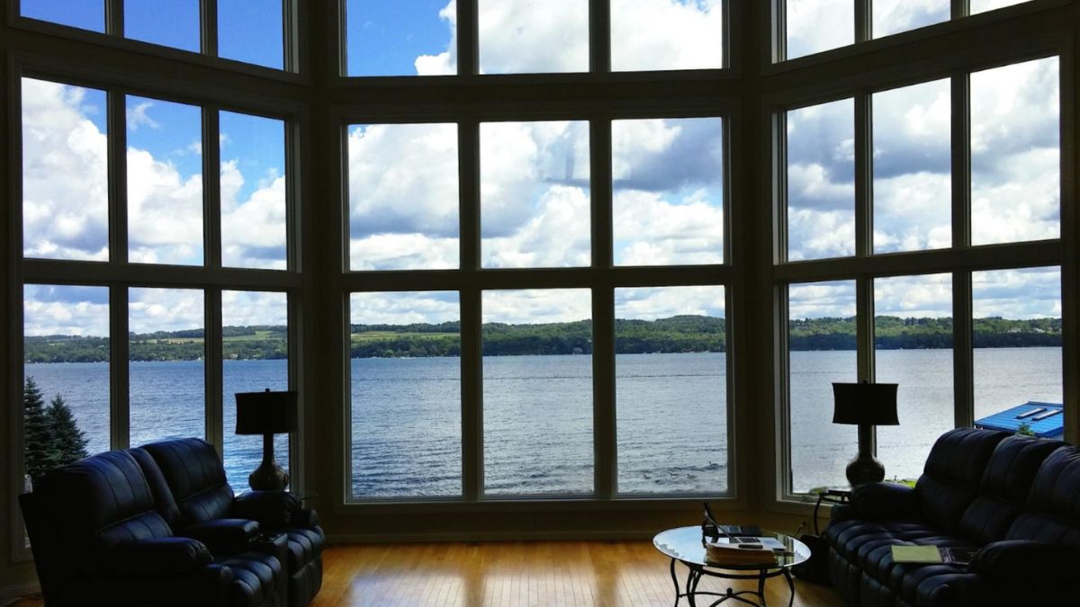 Stylish living room featuring large bay and bow windows by HHI Windows and Doors, with a captivating view of the lake.