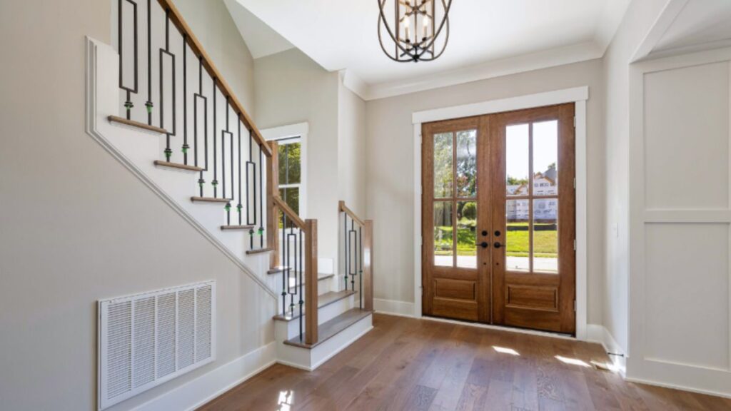 A hallway featuring a staircase, wooden flooring, and elegant French doors creating a warm and inviting atmosphere.