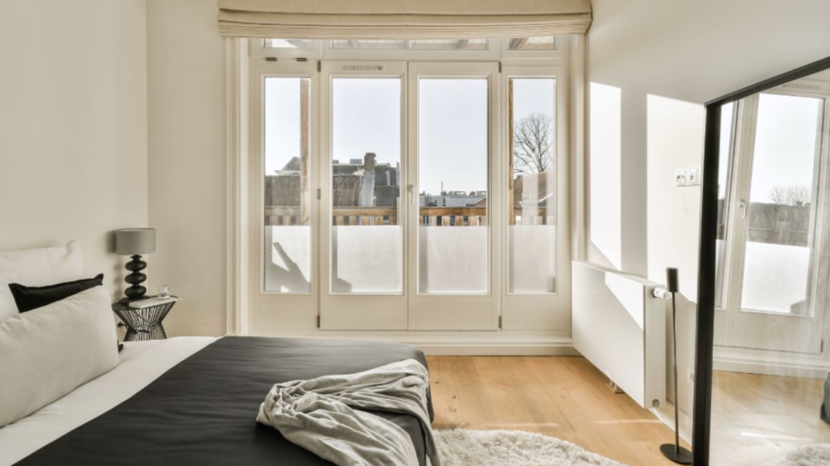 A cozy bed adorned with a black and white blanket, positioned near elegant French doors.