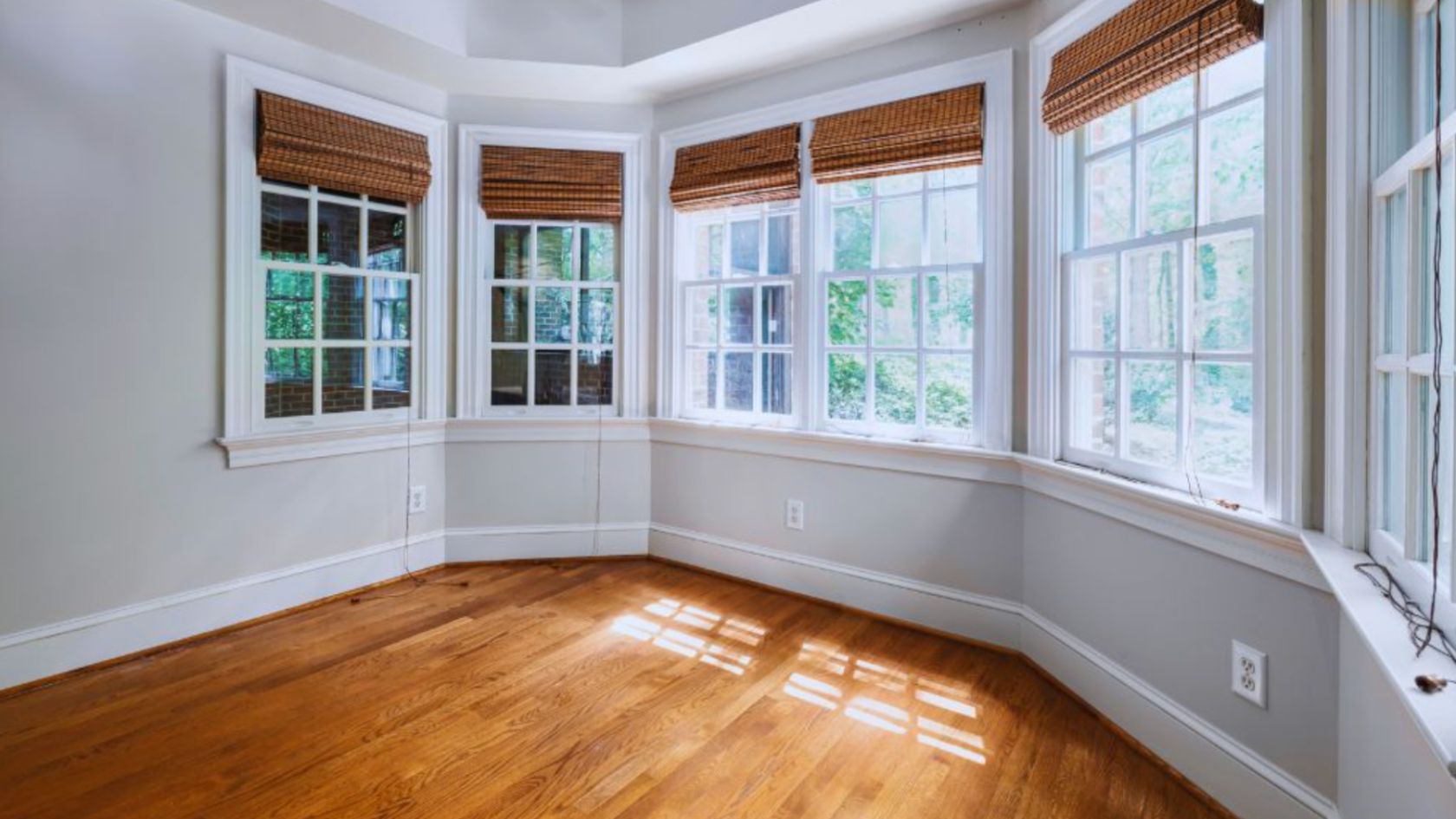 A room featuring hardwood floors and single-hung windows, allowing natural light to illuminate the space.