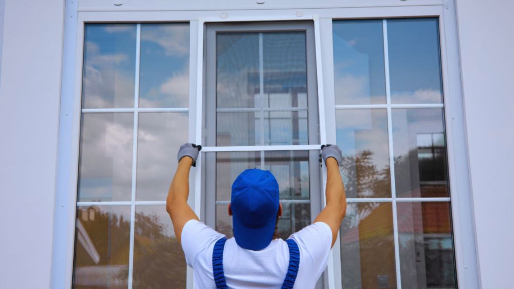 A skilled man, wearing blue overalls and a hat, carefully repairs a single-hung window, showcasing precision and attention to detail.