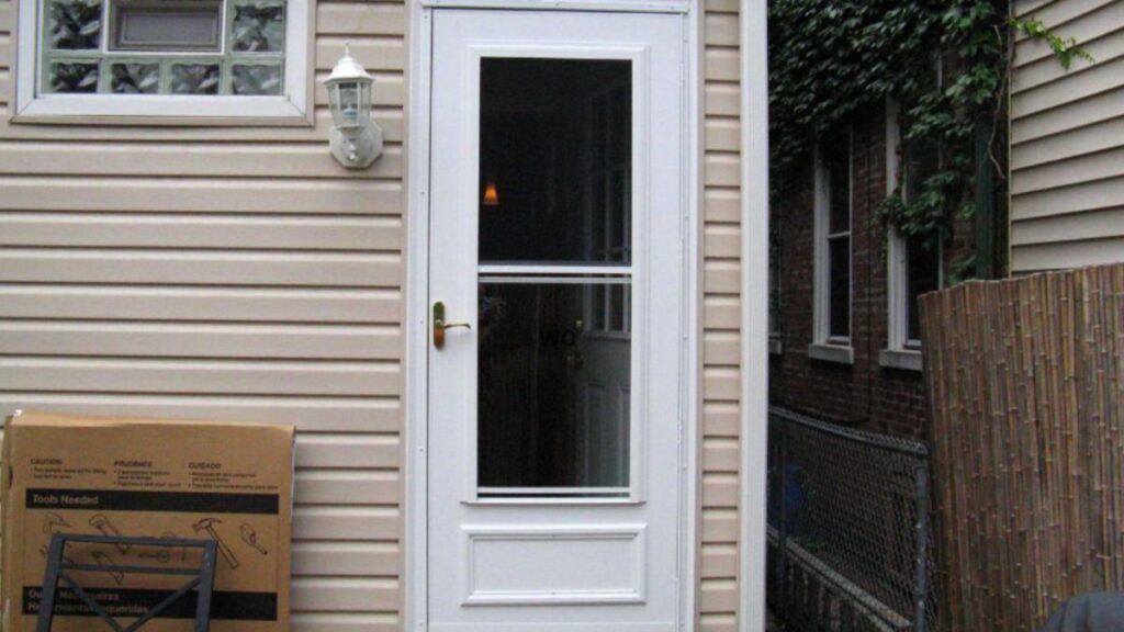 A white storm door in the backyard features a window, providing a view while enhancing home security and aesthetics.