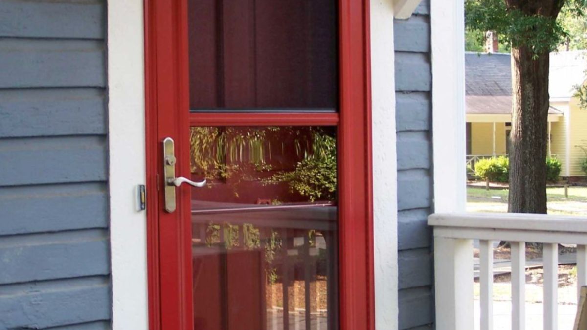 A striking red entry door protected by a storm door enhances the porch's appeal.