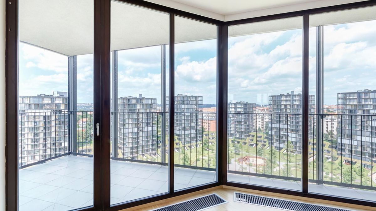 A large glass door opens to a balcony with a city view, showcasing modern window installation techniques.