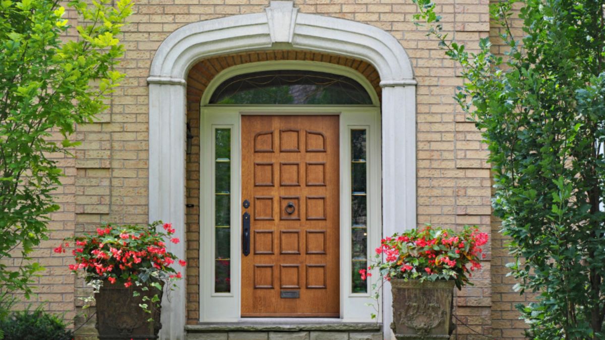 Transom windows and sidelights frame the entry door to achieve a classic charm and bring more natural light into the home.