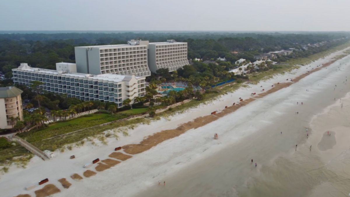 Aerial view of a beach and hotel in Hilton Head, SC, showcasing the coastline and resort amenities.