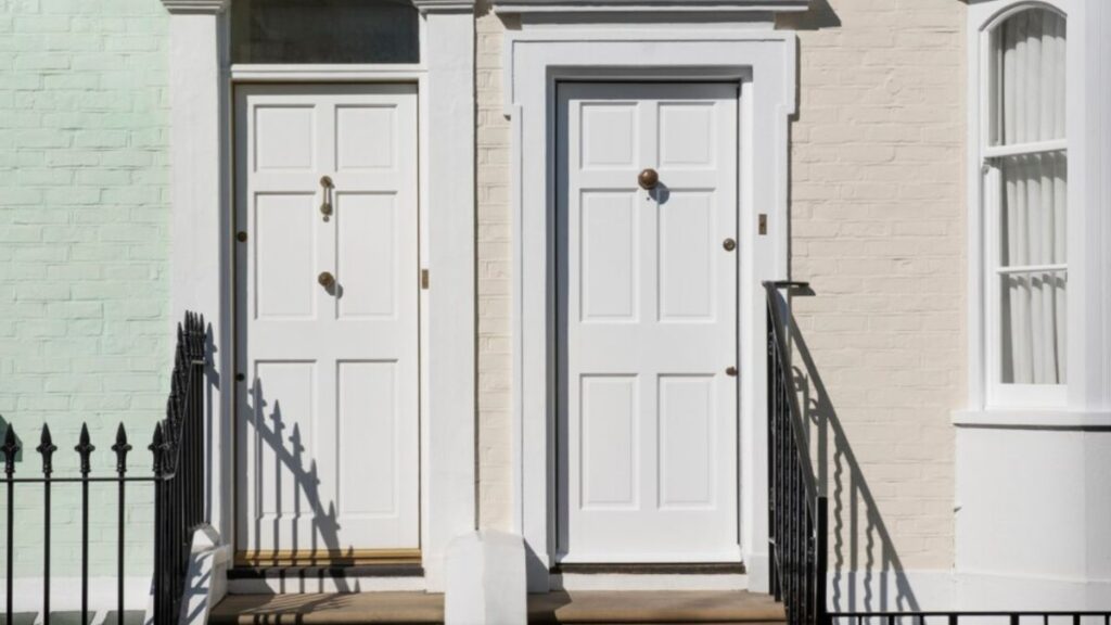 Two elegant white entry doors with glass panels set against a brick facade showcasing the window and door services available in Okatie, SC.