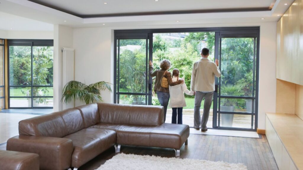 A family gazes out through patio doors, enjoying the view from their home together.