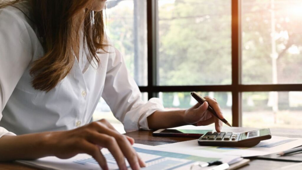 The woman is at her desk reviewing home window financing documents with focus and care.
