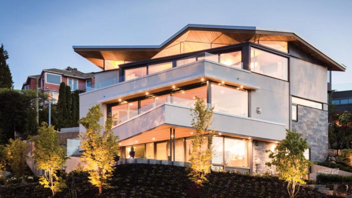 Modern home featuring a large glass wall and an expansive deck, highlighting contemporary architecture and outdoor living spaces.